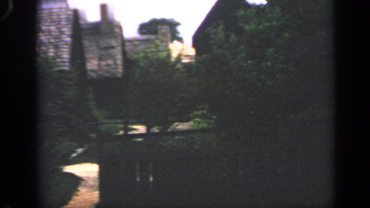 Dark stone buildings and trees beside a narrow path.