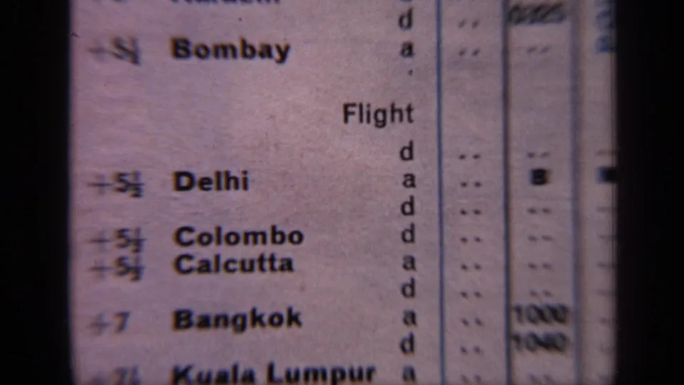 Close 8mm view of a vintage flight schedule page, with Bombay, Delhi, Colombo, Calcutta, and Bangkok legible.