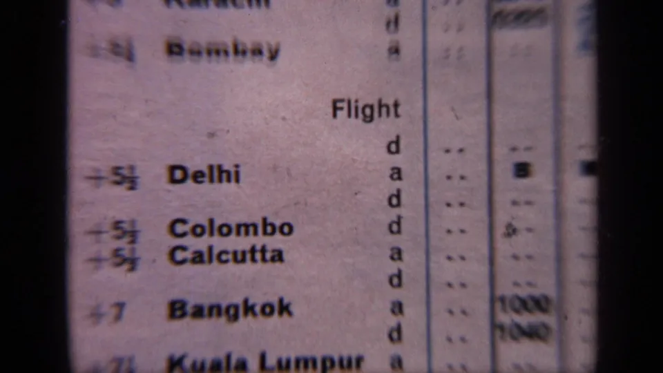 1970 India travel footage frame showing a soft, grainy close-up of the printed schedule and destination list.