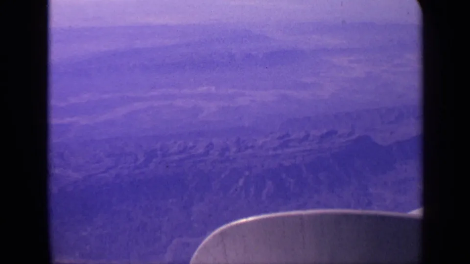Faded 8mm aerial view over India, with a curved airplane wing edge at the bottom and rugged ridges beyond.