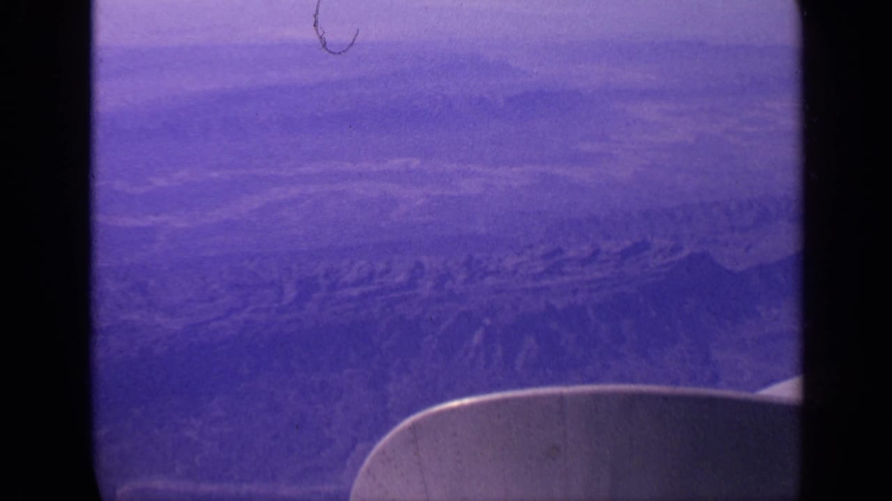1970 India 8mm aerial view showing hazy desert terrain, rugged ridges, and the edge of an airplane wing.
