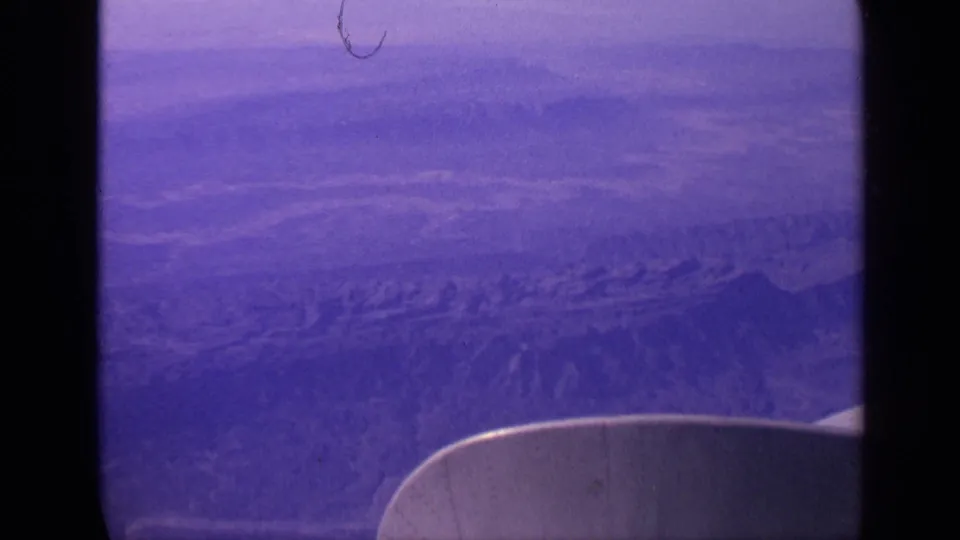 1970 India 8mm aerial view showing hazy desert terrain, rugged ridges, and the edge of an airplane wing.