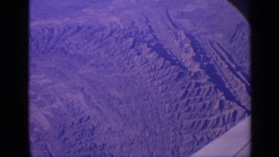 1970 8mm frame of a terrain-like purple-blue surface, with darker channels and the contact-sheet divider visible at left.