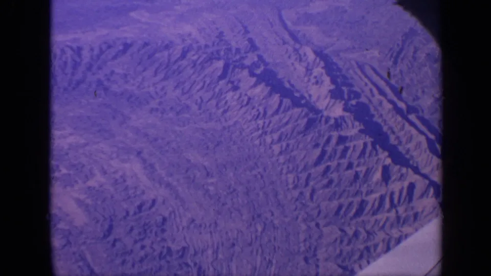 1970 8mm frame with a purple-blue surface-like view, black borders, and soft projected-film texture visible across the frame.