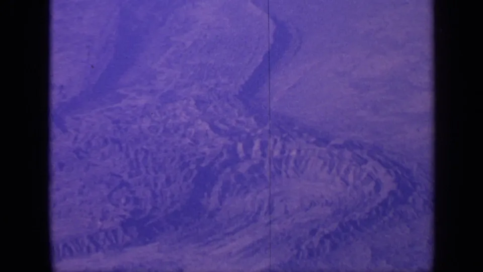 1970 India airplane-window view with hazy mountain ridges, valley shapes, and visible 8mm film texture.