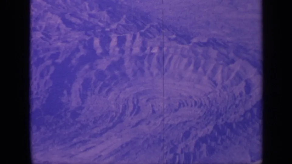 1970 India 8mm frame showing rugged concentric terrain from above with aged purple color shift.