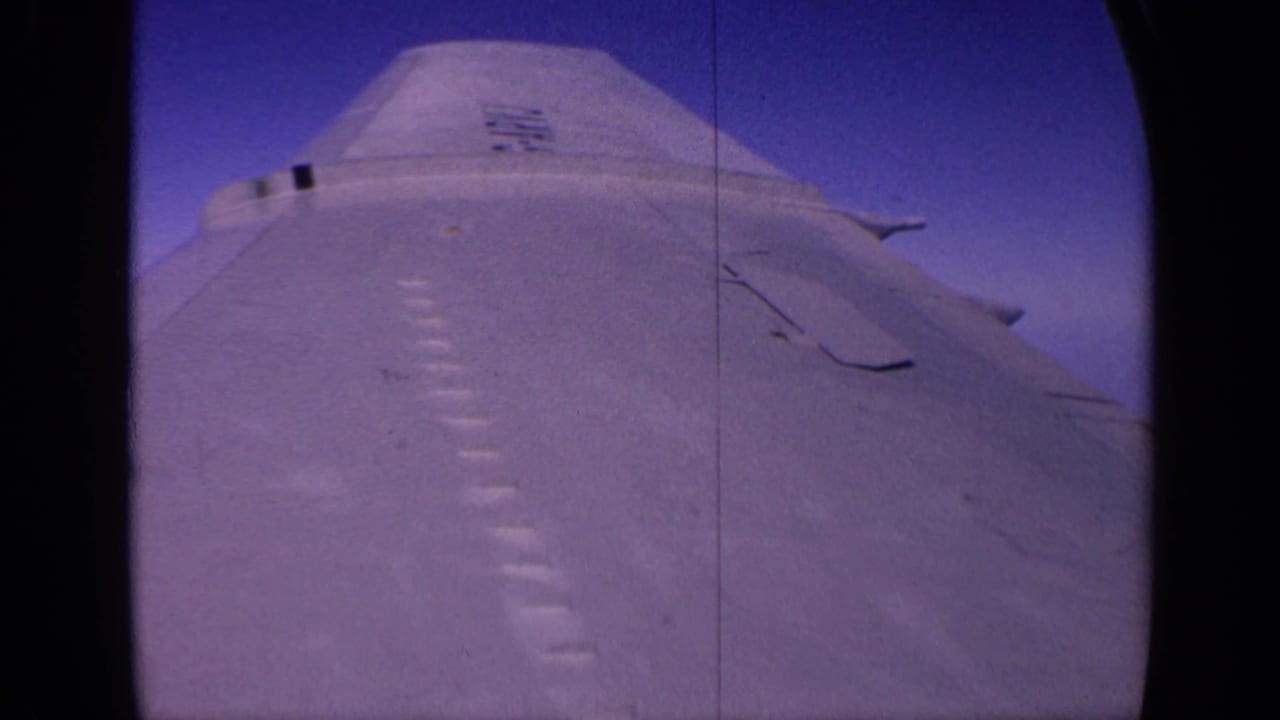 1970 India 8mm frame showing a pale military aircraft fuselage and wing surface against deep blue sky.