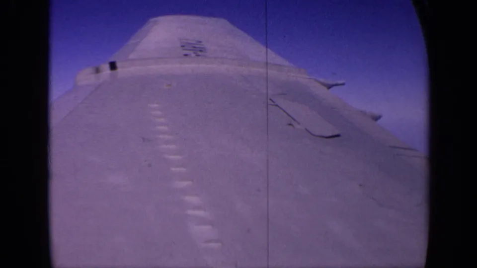 1970 India 8mm frame showing a pale military aircraft fuselage and wing surface against deep blue sky.