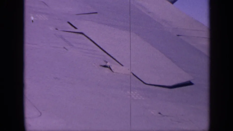 1970 India 8mm still showing the aircraft wing and surface lines with a strong purple-blue color cast.