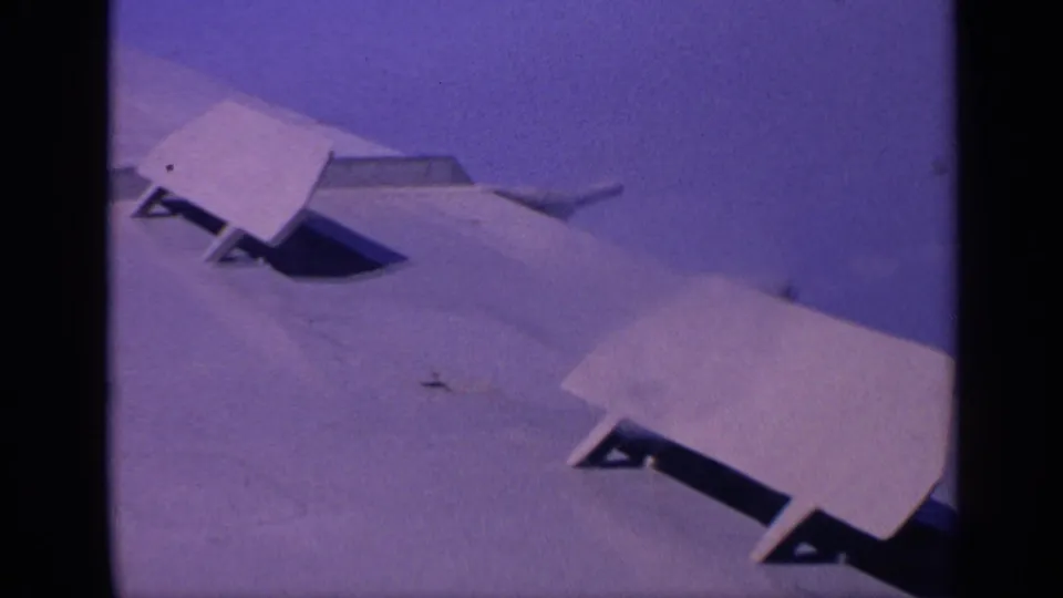 1970 India 8mm view of the aircraft wing surface, showing flap panels and mechanical openings in soft purple-tinted color.