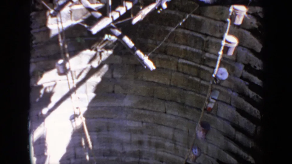 Close view of a stone well with suspended ropes and containers, shown in vintage 1970 India home-movie footage.