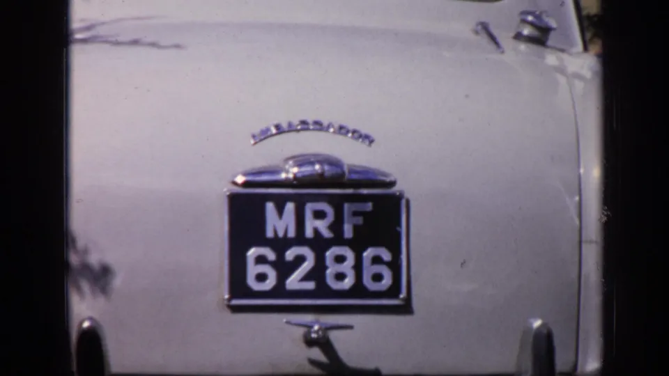 Close rear detail of a white Ambassador car in India, with chrome trim and black license plate reading MRF 6286.