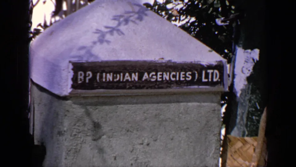 Close view of a concrete pillar in India with a visible BP (Indian Agencies) Ltd sign and surrounding trees.