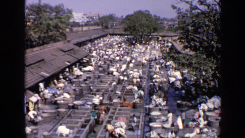 Elevated 1970 India view over a busy market beside railway roofs, with many people and goods visible.