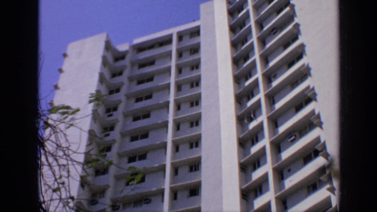 Low-angle view of a white multi-story apartment building against a blue sky.
