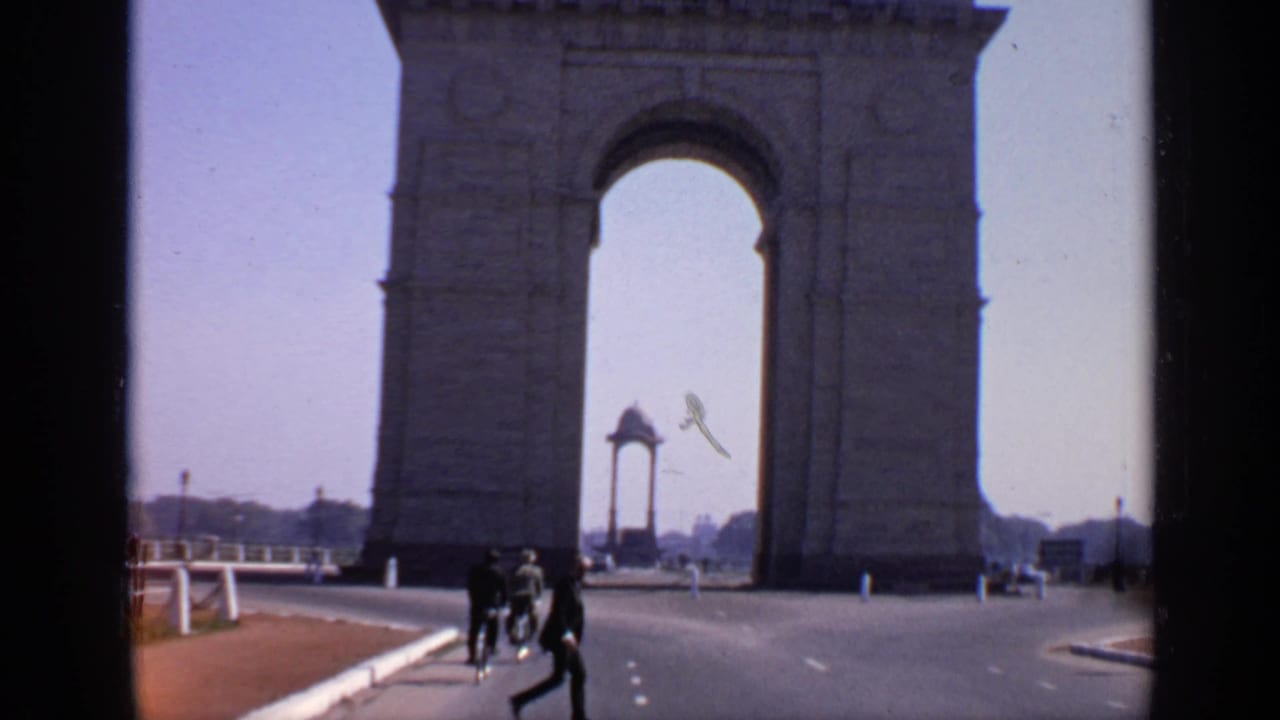 India Gate seen across a wide road with pedestrians moving near the arch.