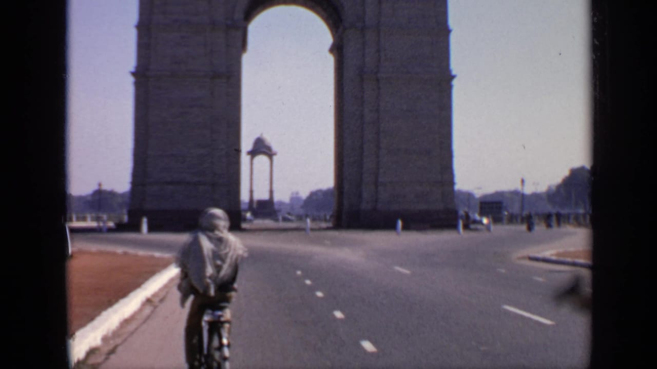 A cyclist moves along the road near India Gate in New Delhi, with the arch, curb, and a few distant vehicles visible.