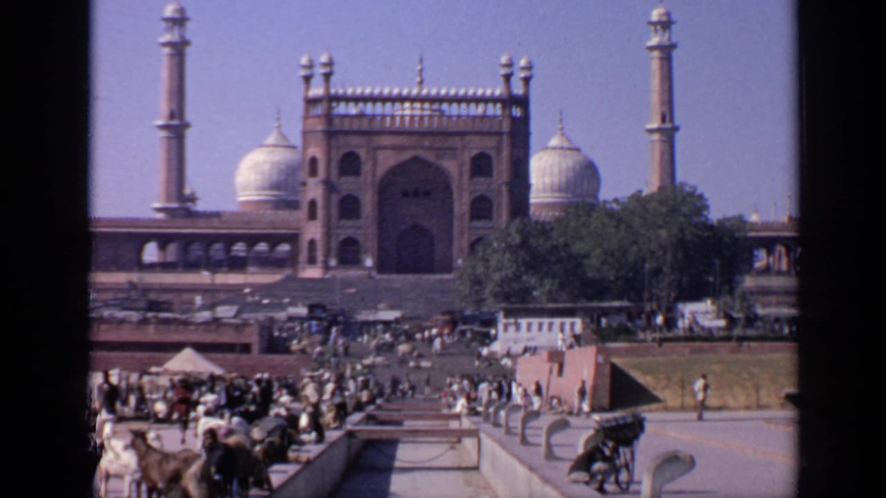 Crowded plaza before a large mosque with domes and minarets.