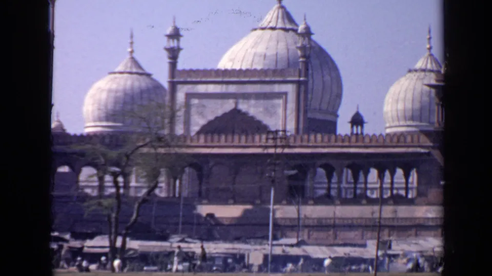1970 India travel frame showing a closer view of Taj Mahal domes and arches with trees and visitor activity along the bottom.