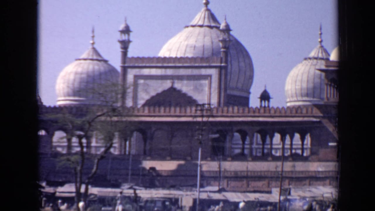 Domed mosque facade seen through a dark vertical window frame.