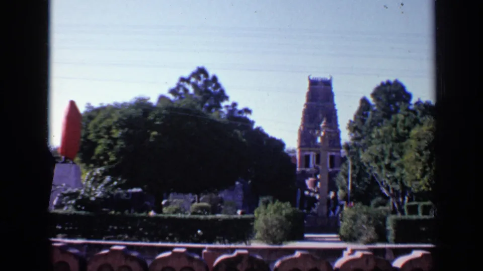 A wider 1970 India garden view shows the red-covered object at left, hedges, trees, a path, and a distant temple-like tower.