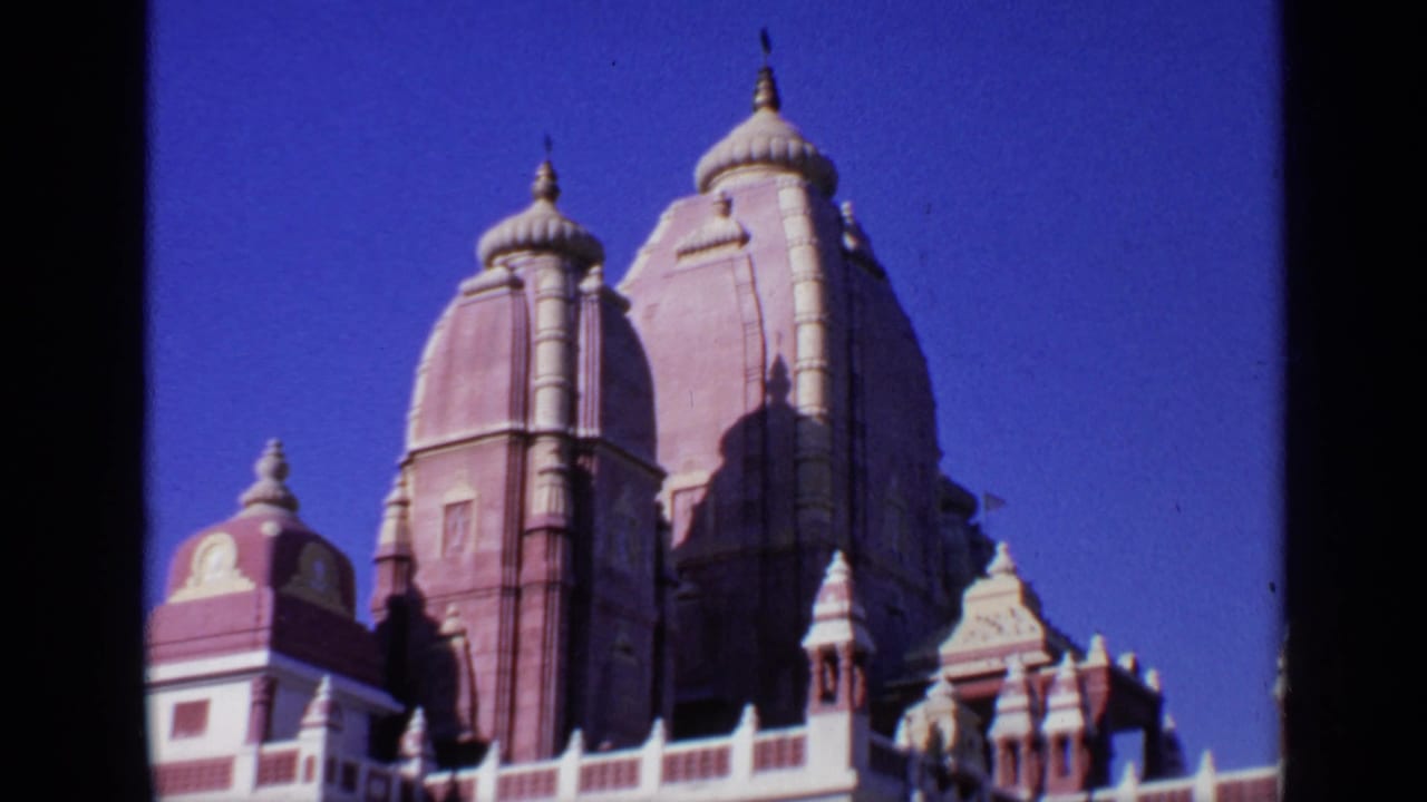 Low-angle view of red and white temple towers against a blue sky.