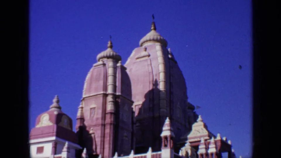 1970 India 8mm frame focused on tall red and white temple towers, filmed from a low handheld angle.