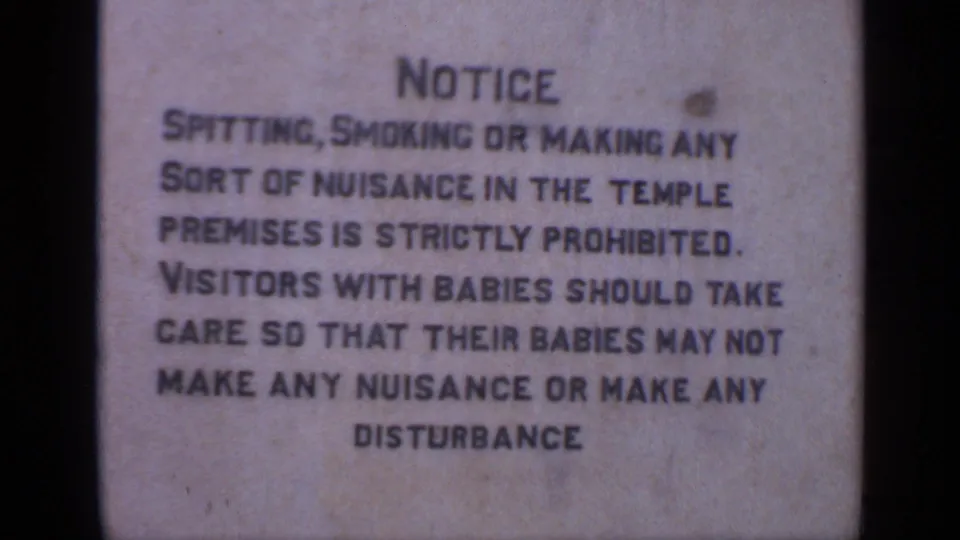 A temple-premises notice in India warns against spitting, smoking, nuisance, and disturbance, with soft 8mm focus.