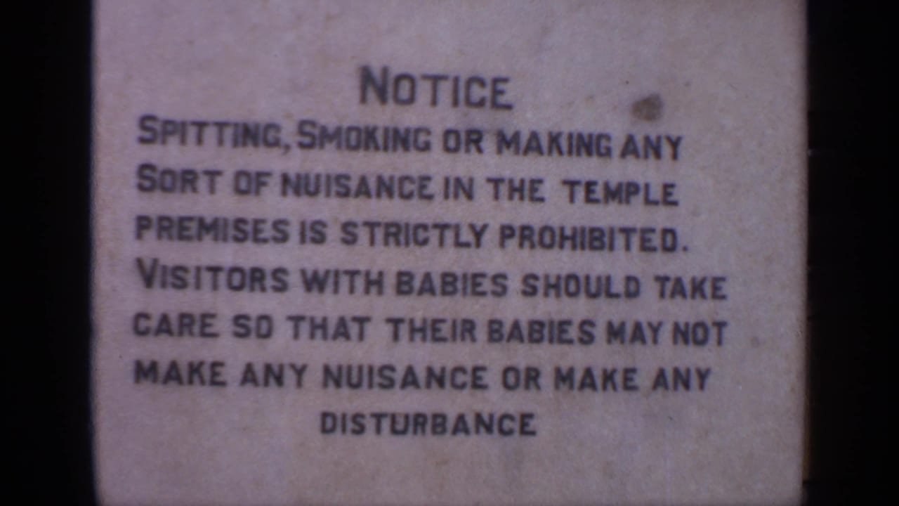 Close view of a weathered temple notice with black lettering.