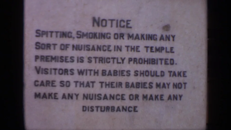 1970 India 8mm frame showing a metal temple notice prohibiting spitting, smoking, nuisance, and disturbance.