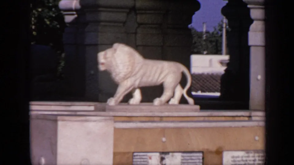 1970 India 8mm frame showing a white lion statue facing right on a temple pedestal under arched stone architecture.