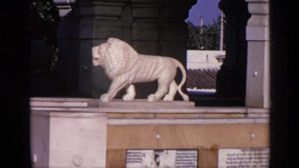 The white lion statue remains centered on its pedestal, with temple columns, plaques, and a shadowed arch behind it.