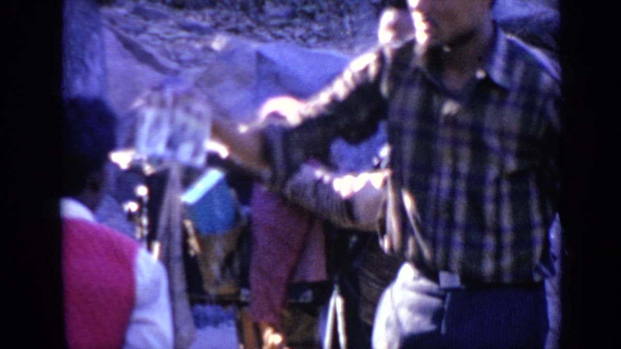 Visitors near a tripod camera, including a man in plaid shirt and blue pants.