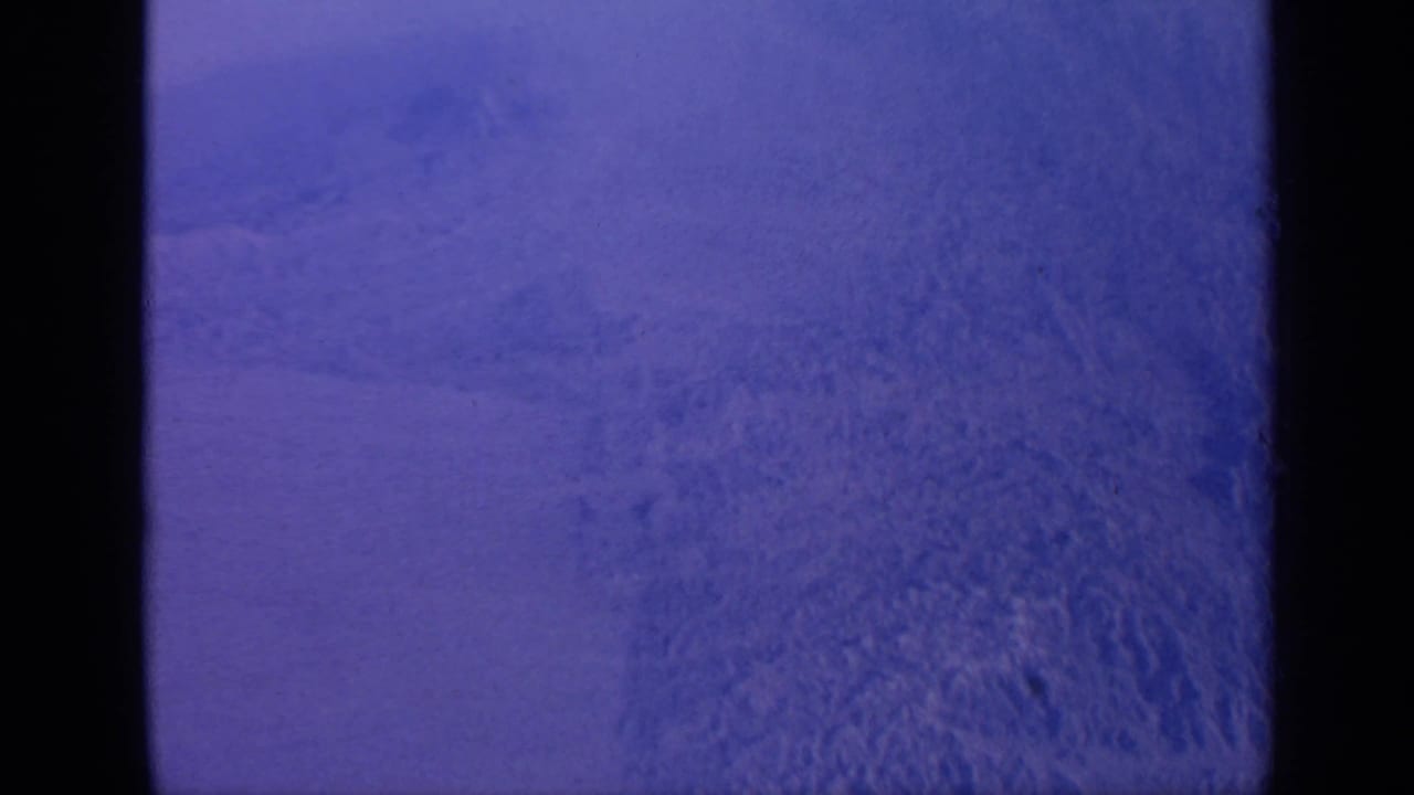 1970 India home-movie frame showing a static snow-covered mountain surface with purple-blue color cast and visible film gate edges.