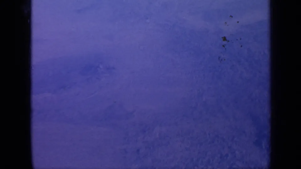 Static 1970 India snow landscape with faint ridgelines, pale sky, soft grain, and dark Super 8 frame borders.