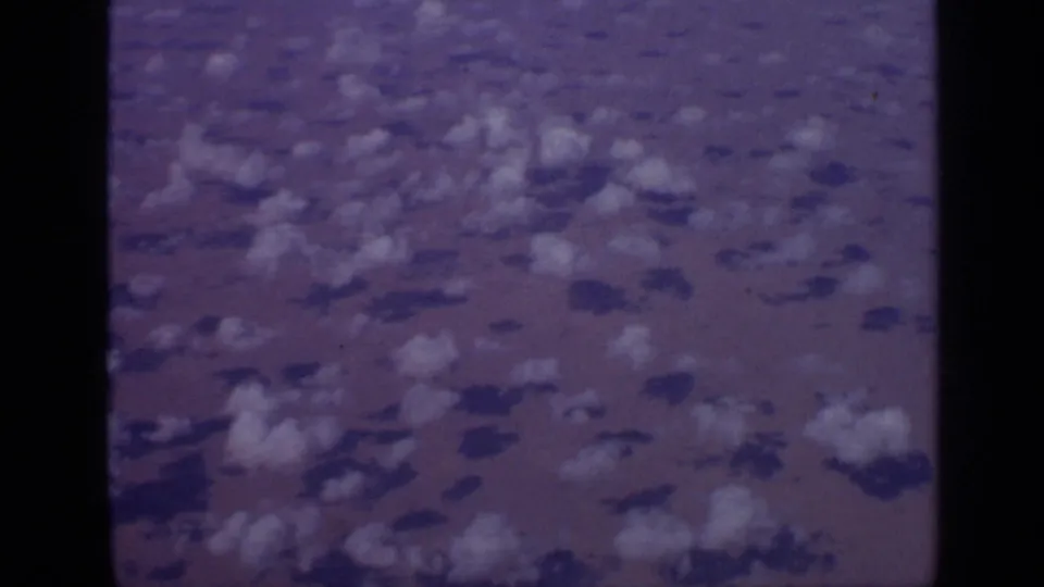 1970 India aerial frame with scattered clouds casting shadows across reddish arid ground.