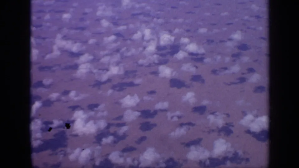 1970 India 8mm frame showing a wide desert surface with scattered clouds, soft shadows, and dark gate edges.