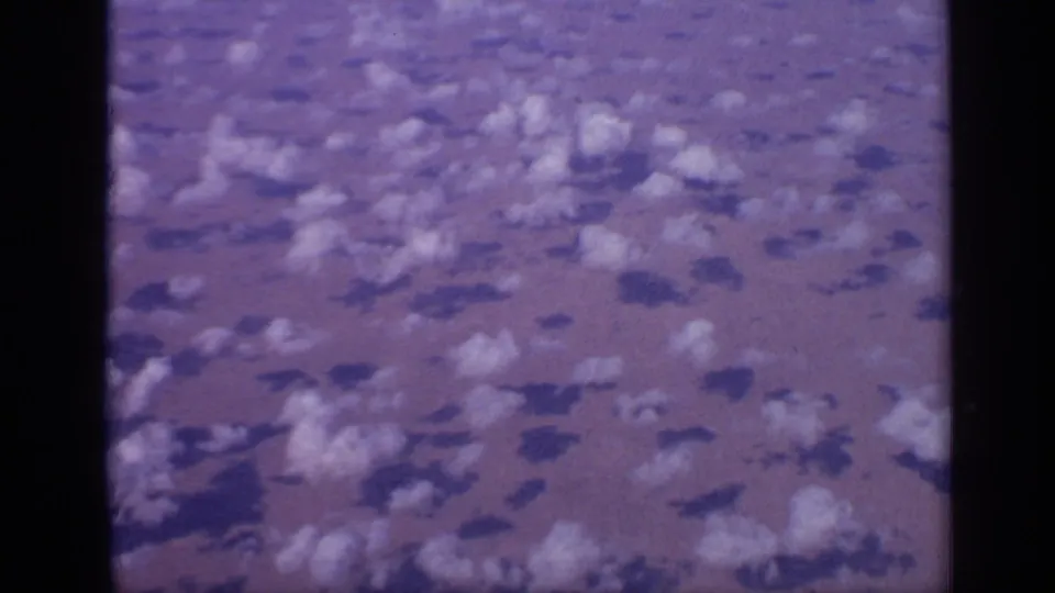 1970 India aerial frame showing scattered clouds over arid terrain, bordered by dark aircraft-window or film edges.