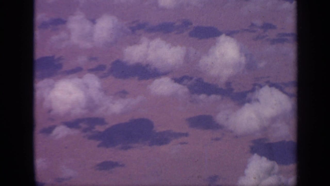 Clouds seen through an airplane window with a purple-pink sky tint.