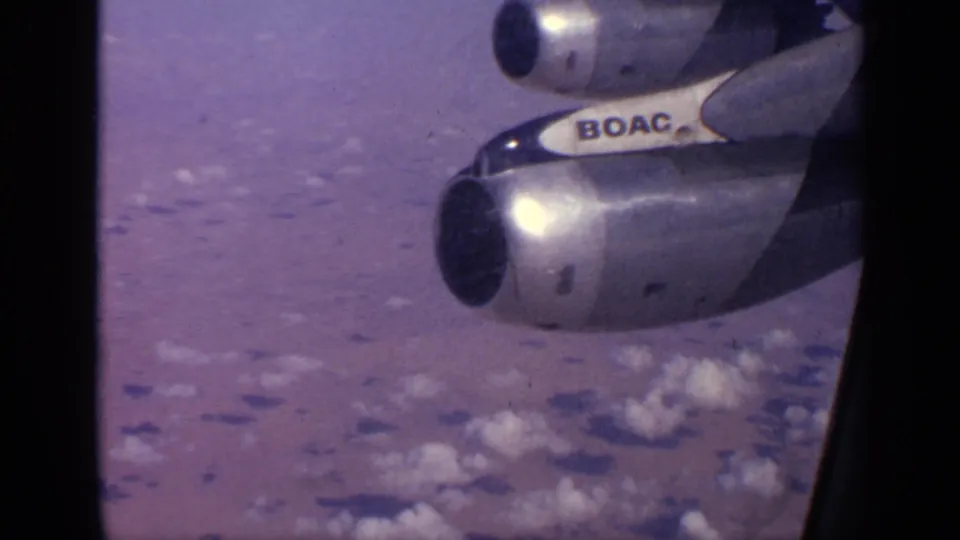 1970 India travel footage shows BOAC lettering and jet engines outside an airplane window above scattered clouds.