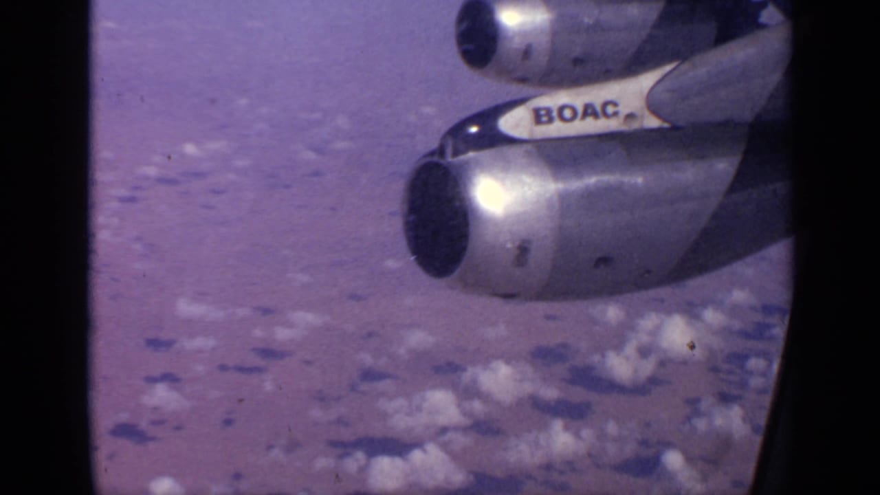 1970 8mm passenger-window view over India showing BOAC-marked aircraft engines above clouds and distant terrain.