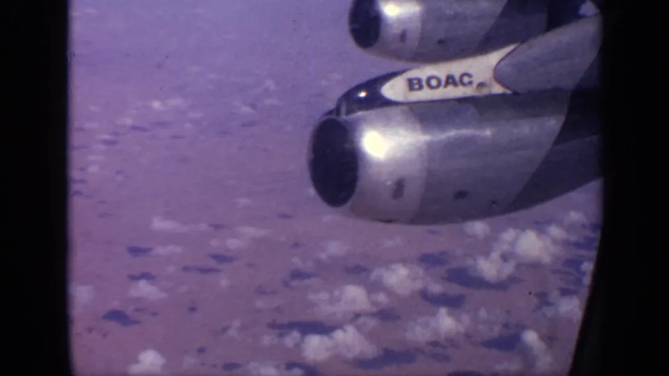 Passenger-window view from a 1970 India home movie, with BOAC lettering on the aircraft and clouded terrain below.