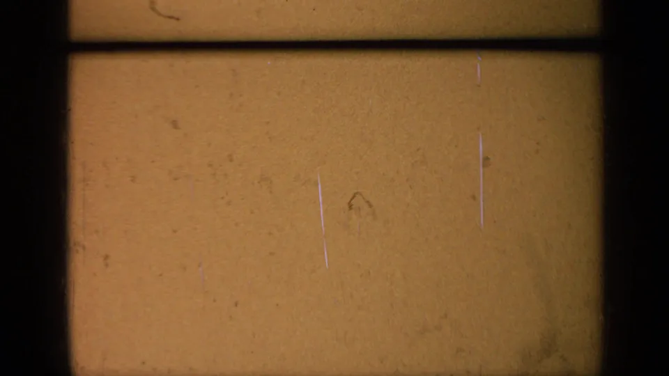 End-of-roll 8mm frame with amber film texture, dust, scratches, and dark gate lines, with no identifiable subject visible.