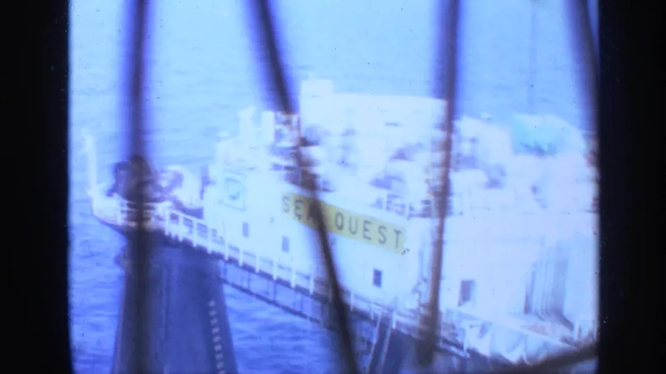 1970 United Kingdom 8mm view of the vessel SEA QUEST at sea, filmed through dark vertical bars with strong overexposure.