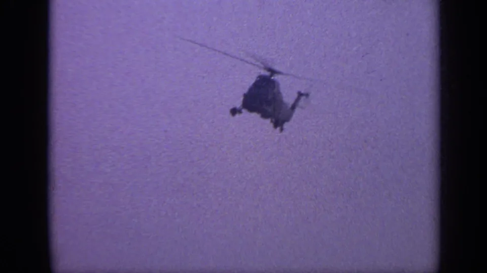 1970 United Kingdom 8mm frame with the helicopter receding as a dark shape against a softly exposed sky.