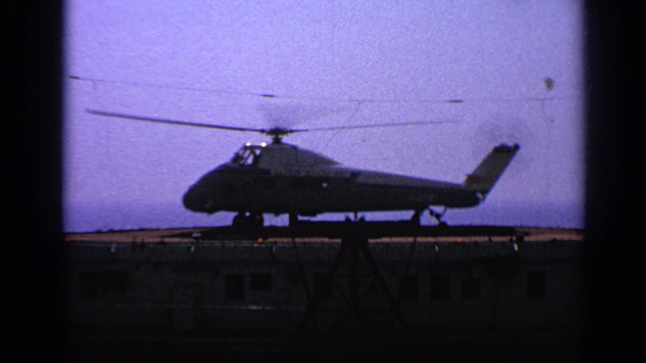 Helicopter silhouette with rotor blades visible above a platform.