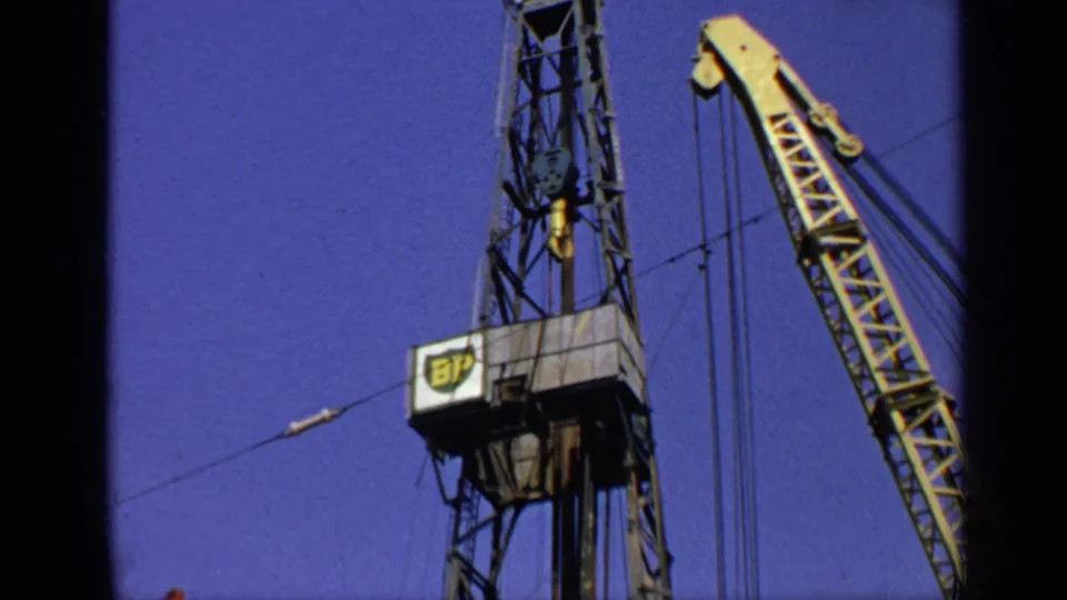 1970 United Kingdom Super 8 frame with the upper BP derrick structure and adjacent yellow crane seen from below.