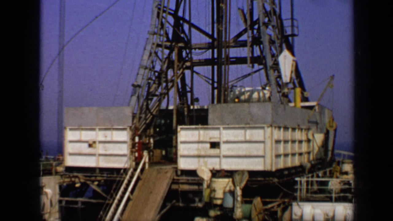 Drilling rig platform with derrick framework, cables and deck equipment.