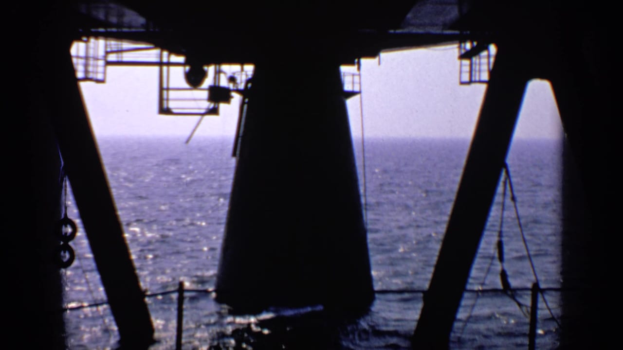 Silhouetted beams frame a bright view of open sea under a hazy sky.