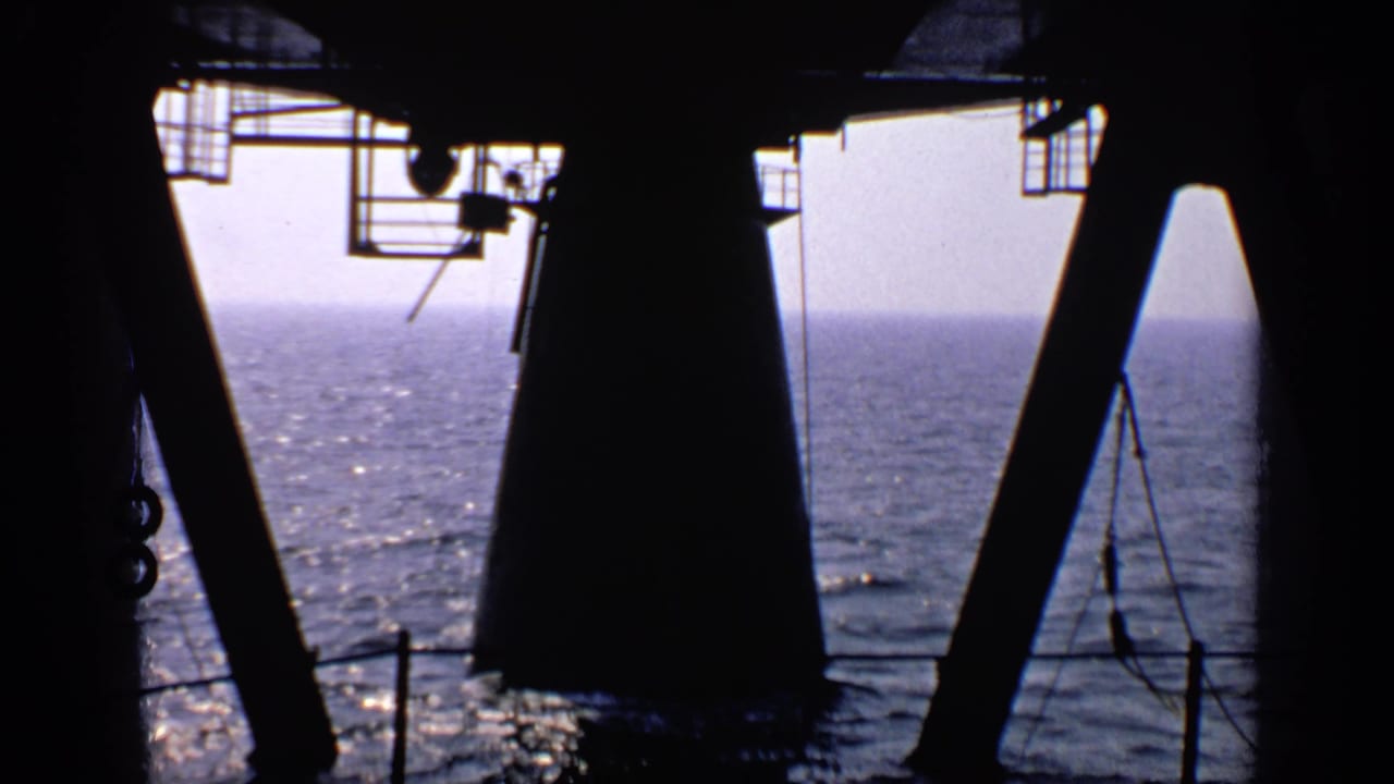 Dark structural supports and railing frame the sunlit sea and horizon.